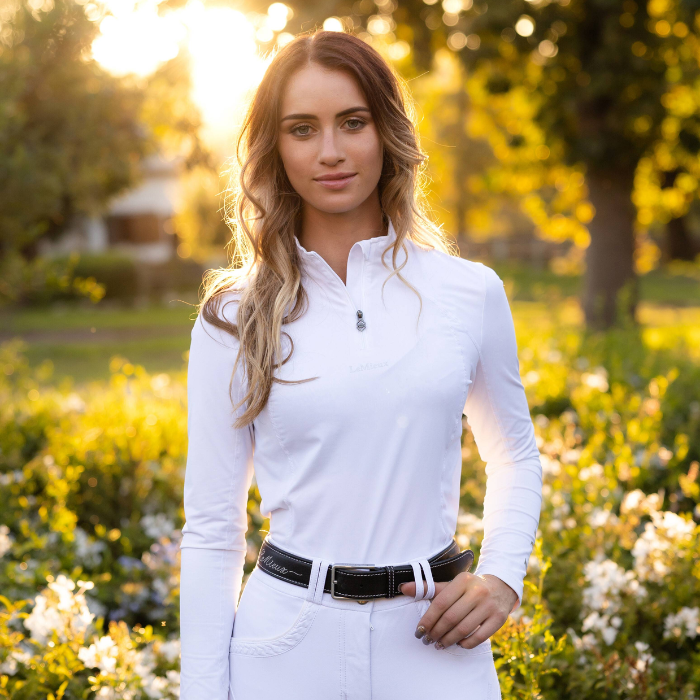 Woman teams the LeMieux Ladies White Base Layer with LeMieux belt and white breeches