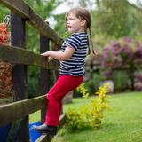 Little girl wears the Shires Childrens Winnie & Me Jodhpurs whilst climbing a  fence