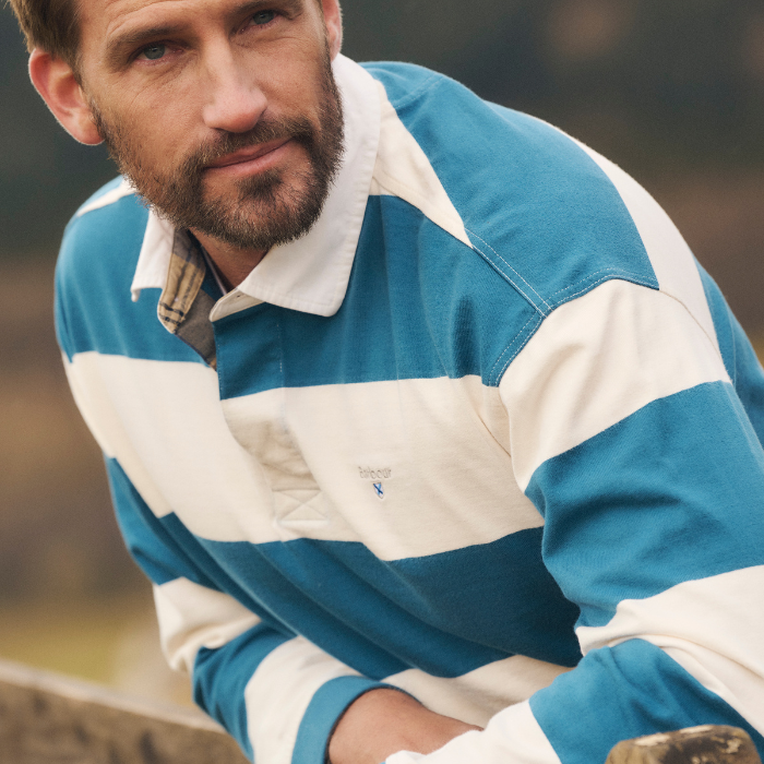 Man leans over a countryside gate wearing the Barbour Broome Rugby Shirt in Midnight