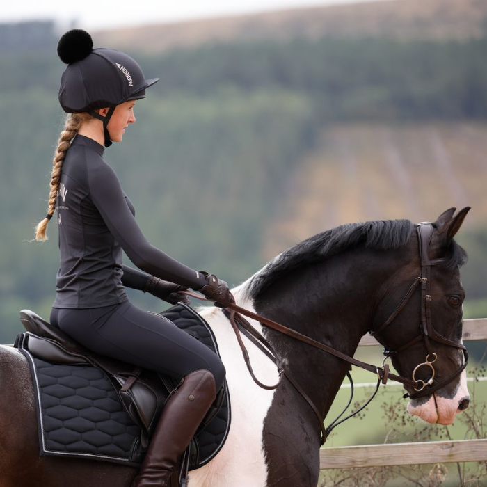 Girl On Horse Wears the Aubrion React Young Rider Long Sleeve Base Layer in Shadow| Eland Lodge