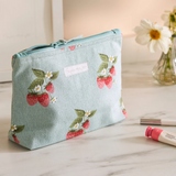 Make up on a counter with the Sophie Allport Makeup Bag with strawberry print