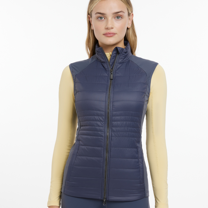 Female styles the LeMieux Ladies Juliette Gilet in Dusk Blue over a yellow base layer