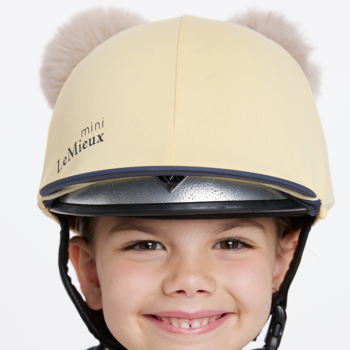 Child wears the LeMieux Mini Double Pom Hat Silk in Mimosa