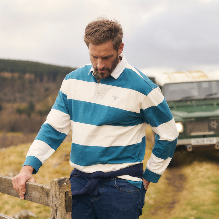 Man strolls through the countryside wearing the Barbour Broome Rugby Shirt in Midnight