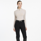 Woman wears the LeMieux Ladies Heyden Lightweight Base Layer in Stone with black breeches