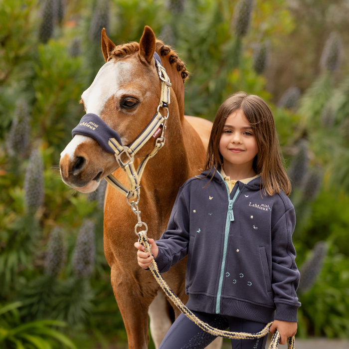 Child stands with cute pony wearing the LeMieux Mini Vogue Headcollar & Leadrope in dusk blue