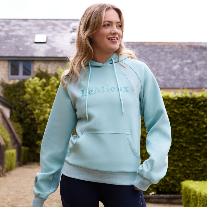 Female in a garden wears the LeMieux Ladies Nadine Hoodie in aqua