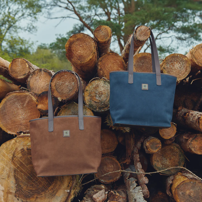 The Dubarry Rosemount Tote Bag in Walnut and Navy hung aesthetically from a log pile