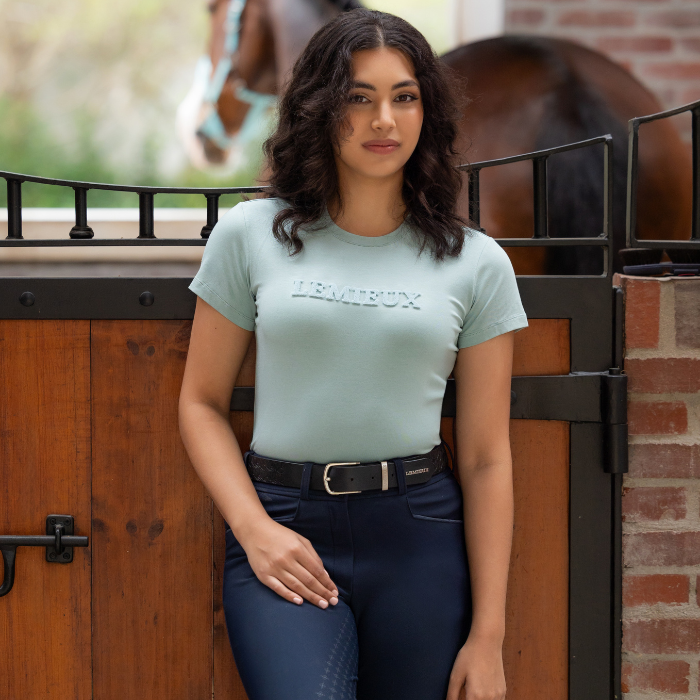 Woman stands by stable wearing the LeMieux Ladies Classique T-shirt in Aqua