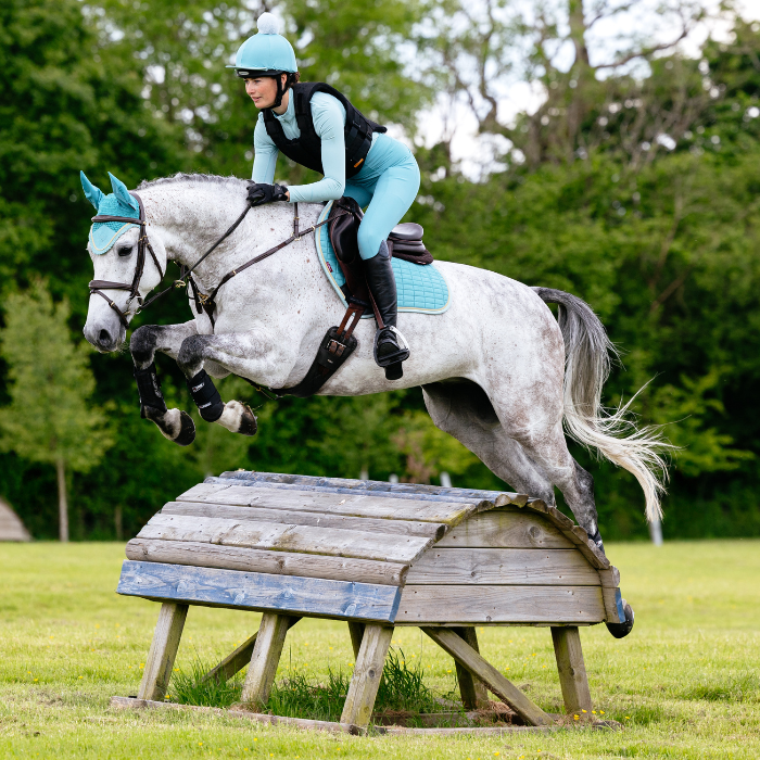 Horse jumps a cross country fence wearing the LeMieux Suede Close Contact Square in Lagoon