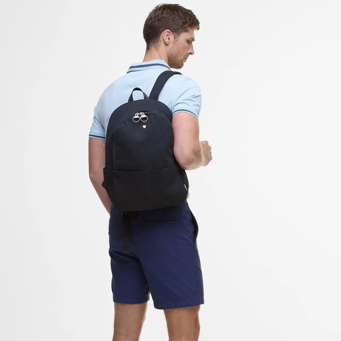 Man wears the Barbour Cascade Backpack in Navy over shoulder