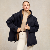 Woman wears the Holland Cooper One-Size Waterproof Jacket in Ink Navy with neutral knit and jodhpur jeans