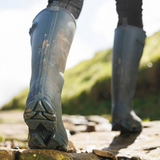 Woman walks outdoors wearing the LeMieux Ultra Stride Wellington Boots in Oak