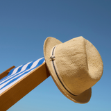 Barbour Mens Bransdale Trilby Hat hung carefully on a blue and white deck chair against a bright blue sky backdrop