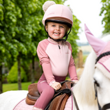 Young girl sits on a pony wearing the LeMieux Mini Base Layer in Blossom