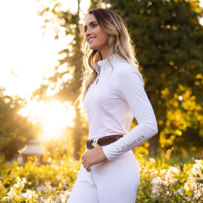 Woman teams the LeMieux Ladies White Base Layer with LeMieux belt and white breeches